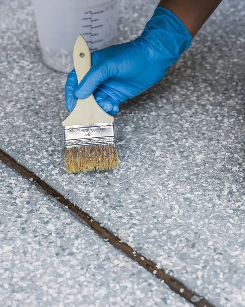 Installer brushing coating into a control joint on a flake floor