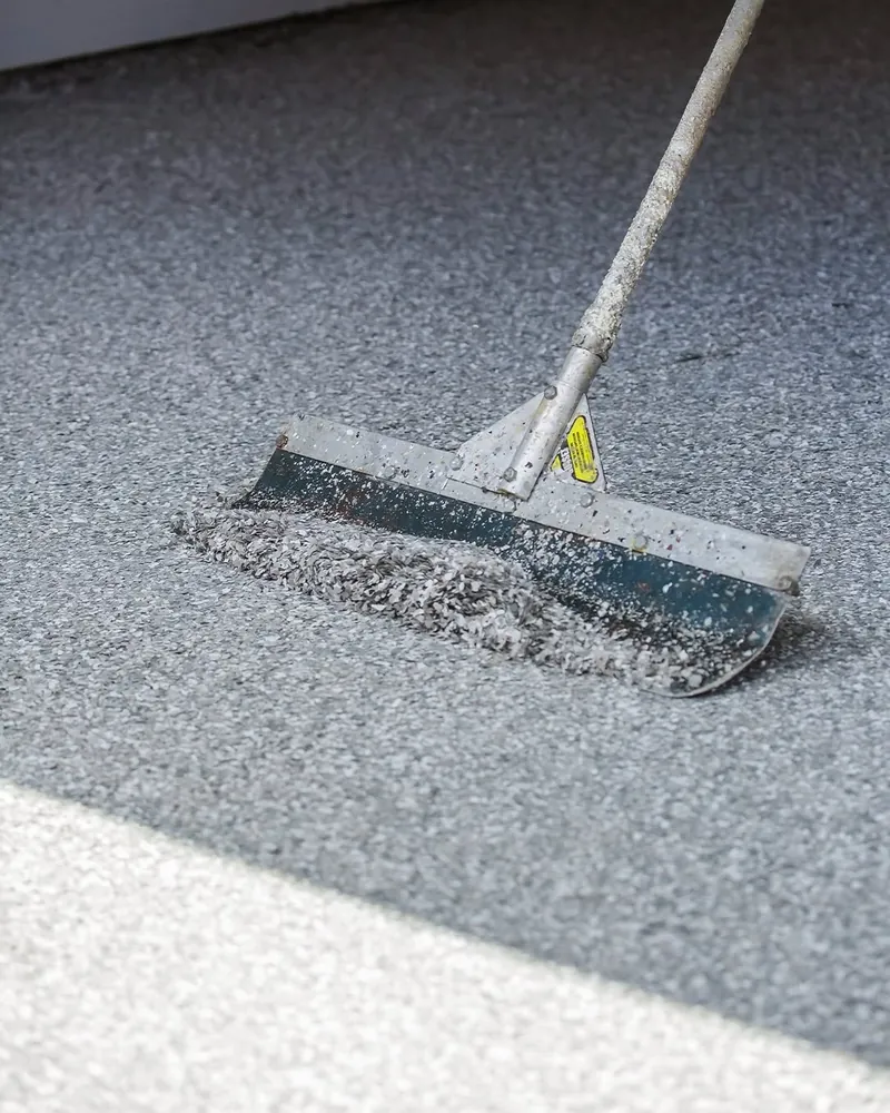 Squeegee spreading decorative flake across a fresh basecoat